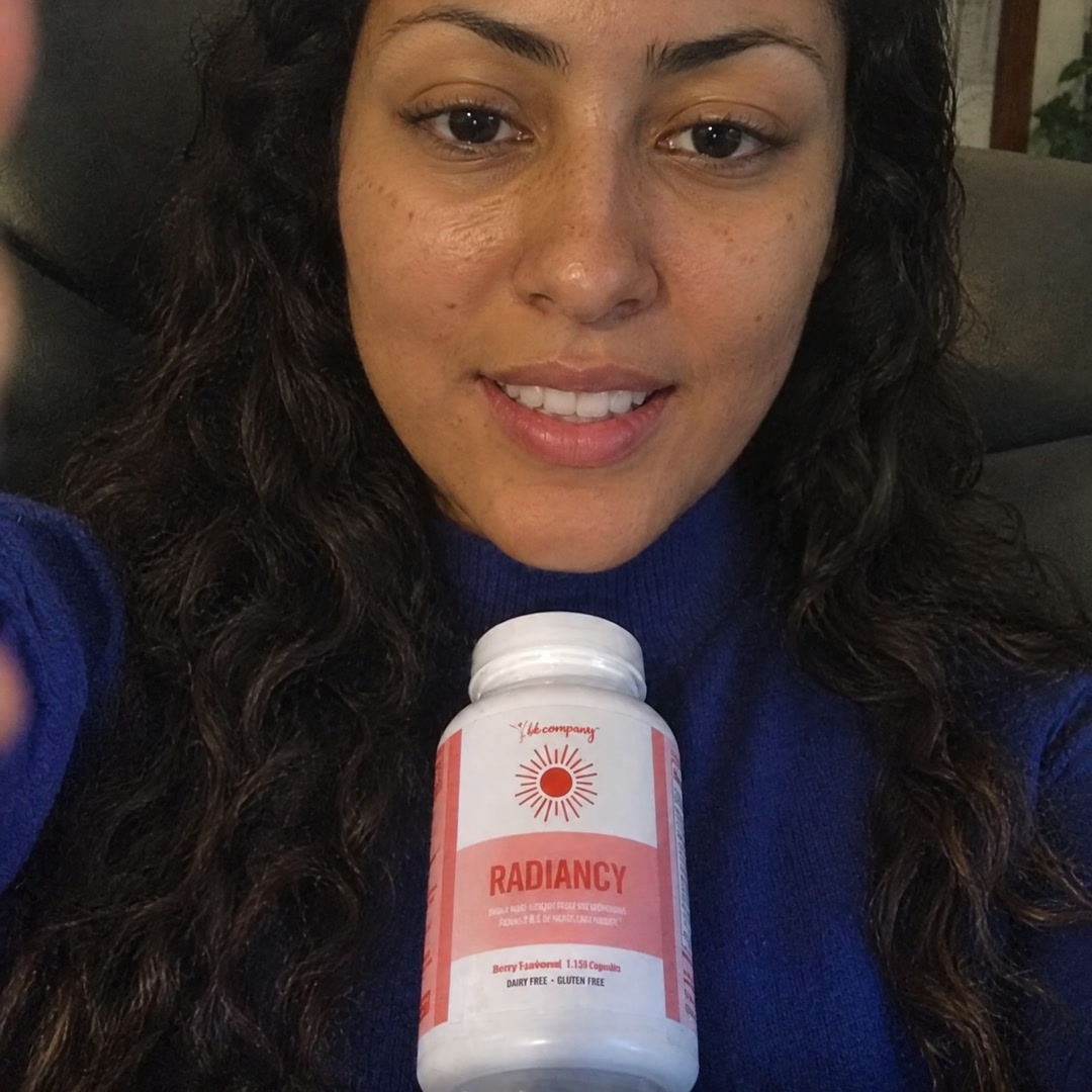 Mulher de blusa azul segurando um frasco de suplemento com o rótulo "Radiancy".